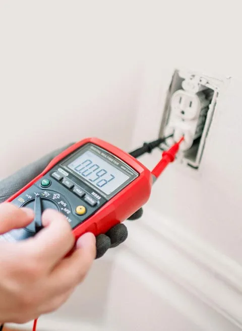 Electrician testing a receptacle during an electrical service call in Toronto.